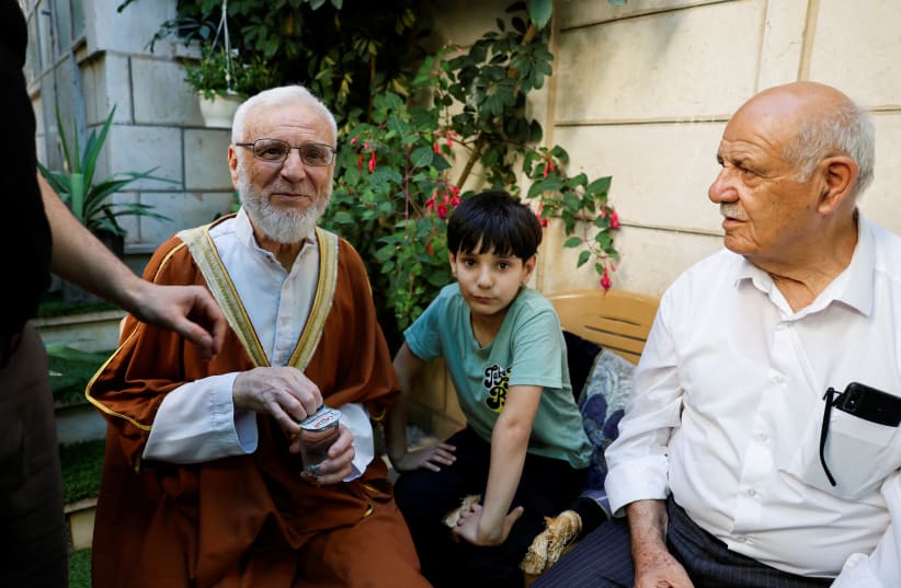 Former Palestinian Parliament Speaker and senior Hamas official Aziz Dweik (left) speaks to his relatives at his house after he was released from the Israeli jail, in Hebron, in the West Bank, June 13, 2024. (photo credit: MUSSA QAWASMA/REUTERS)