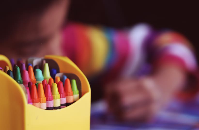  Image of kid drawing on paper behind a case of crayons. (photo credit: PXHERE)