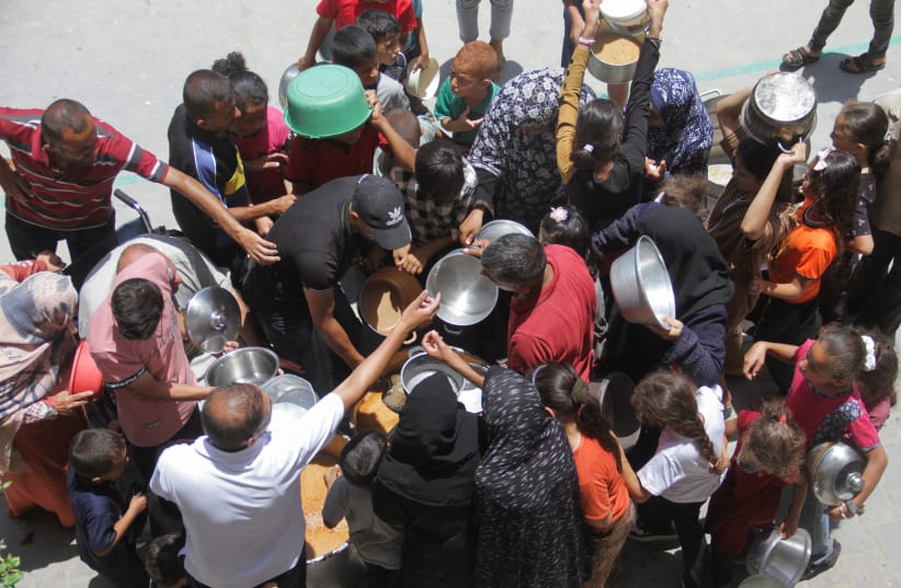  Palestinians gather to receive food cooked by a charity kitchen as the conflict between Israel and Hamas continues, in Jabalya refugee camp, in the northern Gaza Strip, June 19, 2024. (photo credit: Mahmoud Issa/Reuters)