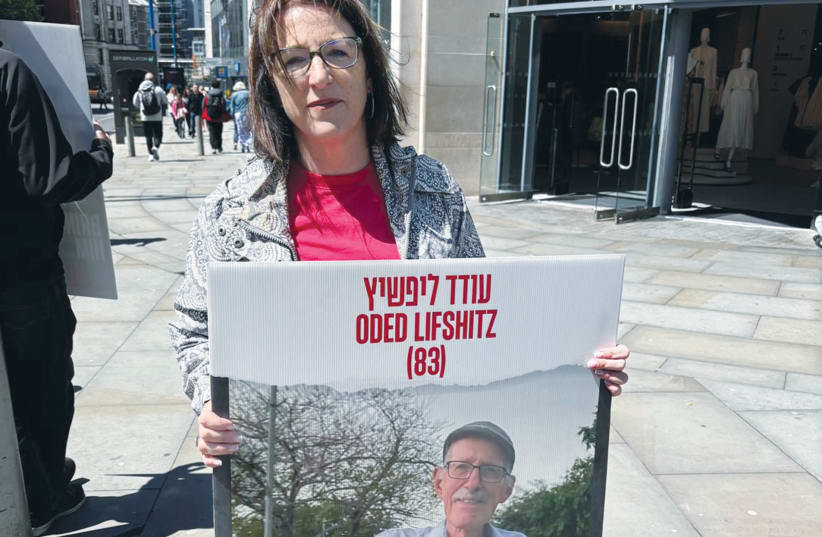  Una cartel con el rostro del rehén Oded Lifshitz, de 83 años, es sostenida por el escritor en la vigilia de los Amigos del Noroeste de Israel en Manchester, el domingo. (photo credit: LEV SAMUELS)