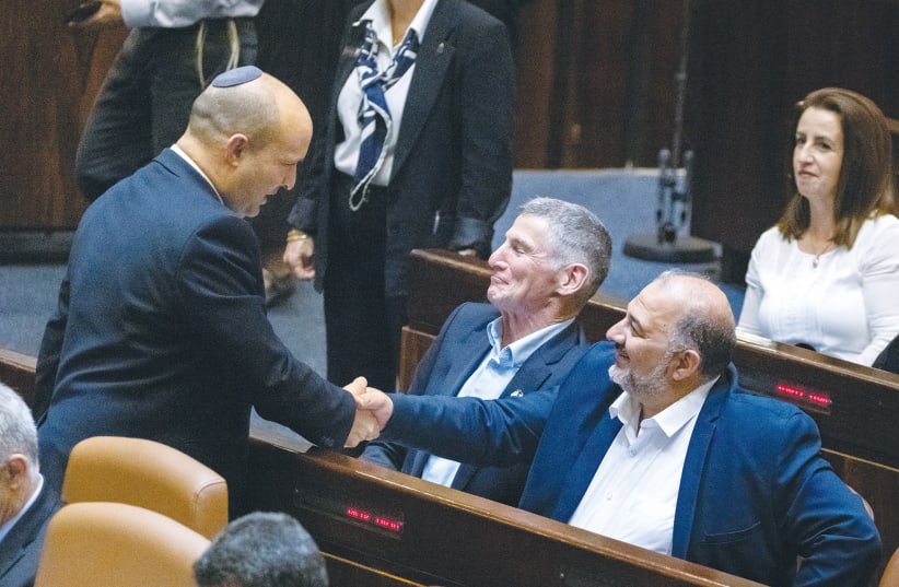  THEN-PRIME MINISTER Naftali Bennett shakes hands with Ra’am Party leader Mansour Abbas in the Knesset plenum, in 2021. (photo credit: OLIVIER FITOUSSI/FLASH90)