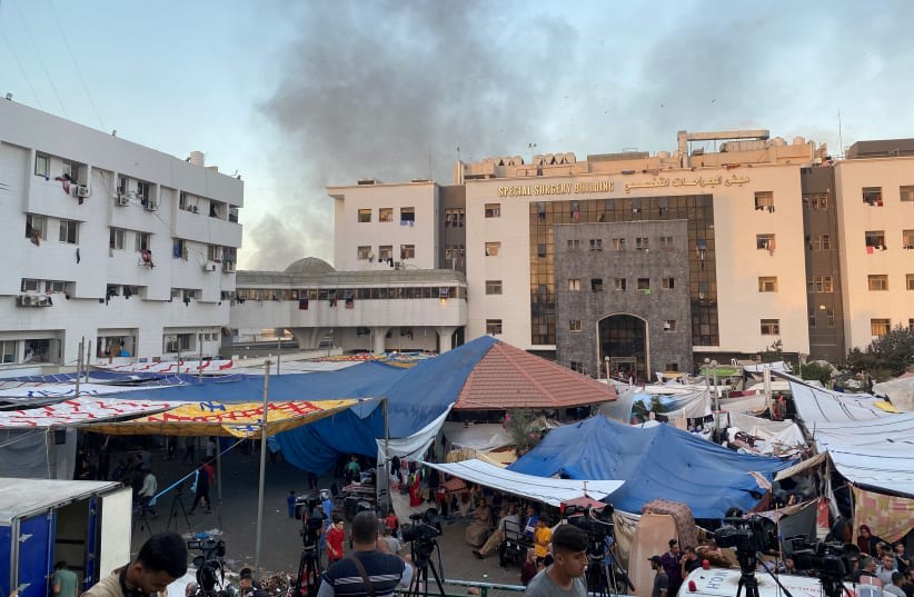  Se levanta humo mientras palestinos desplazados se refugian en el hospital Al Shifa, en medio del actual conflicto entre Hamás e Israel, en la ciudad de Gaza, 8 de noviembre de 2023. (photo credit: REUTERS/DOAA ROUQA)