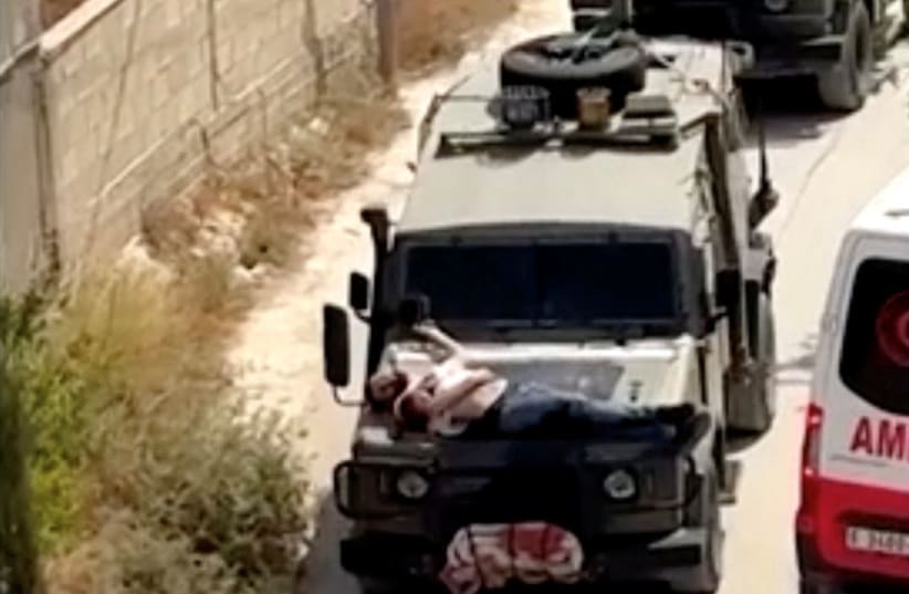  Israeli army straps Palestinian on military jeep during raid in Jenin, in this screengrab from a video, in the West Bank, June 22, 2024. (photo credit: REUTERS/Reuters TV)