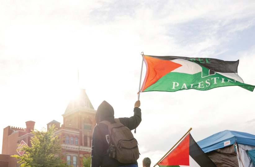  A PROTESTER raises the Palestinian flag at an encampment in support of Palestinians in May at the Auraria Campus in Denver. The pro-Palestinian campaign succeeded in turning the issue from a local conflict into an international matter, the writer notes. (photo credit: KEVIN MOHATT/REUTERS)