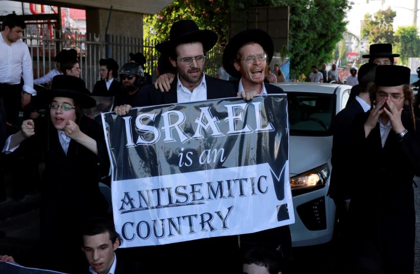  Hombres judíos ultraortodoxos protestan tras la sentencia del Tribunal Supremo israelí que obliga al Estado a comenzar a reclutar en el ejército a estudiantes de seminarios judíos ultraortodoxos, en Bnei Brak, Israel, 27 de junio de 2024. (photo credit: AMMAR AWAD/REUTERS)