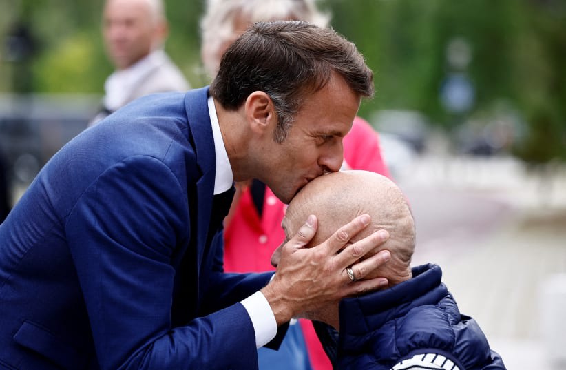  El presidente francés, Emmanuel Macron, besa la cabeza de una persona, a su llegada a un colegio electoral para votar en la primera vuelta de las elecciones parlamentarias anticipadas francesas, en Le Touquet-Paris-Plage, Francia, 30 de junio de 2024. (photo credit: REUTERS/YARA NARDI/POOL)
