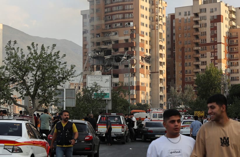  People walk near a damaged building in the aftermath of Israeli strikes, in Tehran, Iran, June 13, 2025 (photo credit: MAJID ASGARIPOUR/WANA)