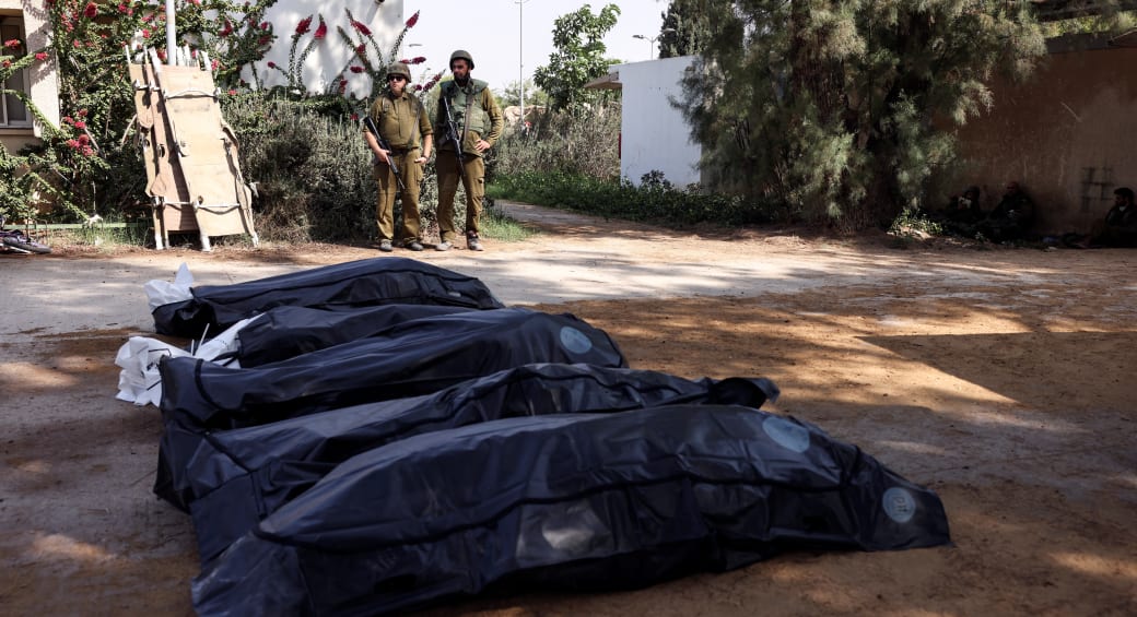  Israeli soldiers guard the bodies of victims of an attack following a mass infiltration by Hamas gunmen from the Gaza Strip, in Kibbutz Kfar Aza, in southern Israel, October 10, 2023. (photo credit: RONEN ZVULUN/REUTERS)