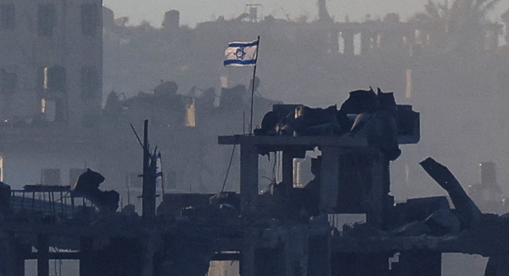  An Israeli flag flutters on a destroyed building in Gaza, as seen from southern Israel, amid the ongoing conflict between Israel and Hamas, November 18, 2023 (photo credit: Alexander Ermochenko/Reuters)