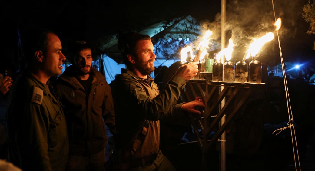 IDF soldiers light the candles of a hanukkiyah amid the ongoing conflict between Israel and Hamas, near Israel's border with Gaza in southern Israel December 13, 2023. (photo credit: RONEN ZVULUN/REUTERS)