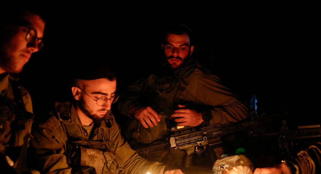  Israeli soldiers light the candles of a Hanukkiyah, near Israel's border with Gaza in southern Israel, December 14, 2023 (photo credit: REUTERS/AMIR COHEN)