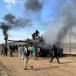  Palestinians react as an Israeli military vehicle burns after it was hit by Palestinian gunmen who infiltrated areas of southern Israel, at the Israeli side of Israel-Gaza border, October 7, 2023. 