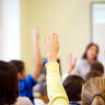 Group of students raising hands during a lesson in the classroom. [Illustrative]