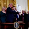 White House senior advisors Ivanka Trump and Jared Kushner, New England Patriots owner Robert Kraft and others stand behind U.S. President Donald Trump as he holds up an executive order on anti-semitism that he signed during a Hanukkah reception in the East Room of the White House in Washington, U.S