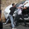 An Israeli police officer runs to rescue an injured Jewish man after his car swerved off road near Jerusalem's Old City after it was pelted by rocks on May 10, 2021