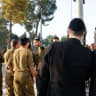  Haredi men dressed in traditional ultra-Orthodox garb stand behind a group of religious IDF soldiers