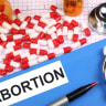  Picture of pills and medical file with the word abortion on it.