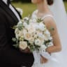 The groom hugs the bride from behind, the bride holds a wedding bouquet. (illustrative)