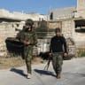  Rebel fighters walk near a military vehicle in Maarat al-Numan in Idlib province, Syria December 1, 2024.