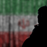 The silhouette of a man, seen over the flag of the Islamic Republic of Iran (illustrative)