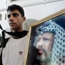 Zakaria Zubeidi posing with his M-16 and a picture of then-Palestinian Authority president Yasser Arafat, in Jenin, July 31, 2004.