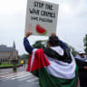 A protester draped in a Palestinian flag holds up a sign at a protest in support of Palestinians in Gaza outside the International Court of Justice (ICJ) in The Hague, Netherlands May 24, 2024.  