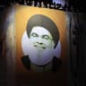 An image of the group's late leader Hassan Nasrallah hangs from a building as people watch atop near the site where Nasrallah was killed, before the first anniversary of his assassination in an airstrike, in Beirut's southern suburbs, Lebanon, September 26, 2025.