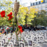 A noose with mock flowers next to portraits of executed Iranian prisoners, and anti-regime activists in the background denouncing Iran's death penalty policies, in Paris, France, October 11, 2025.