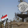 A Syrian national flag flutters next to the Islamic State's slogan in the city of Palmyra, in Homs Governorate, Syria, April 1, 2016 (illustration).