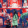 An Iranian woman walk past anti-US mural depicting Iran and US negotiation table, painted on the outer walls of the former US embassy, in Tehran on February 6, 2026. Iran and the United States began talks in Oman on February 6, with Washington refusing to rule out military action against Iran