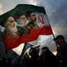 A MAN holds a flag with a picture of late leader of the Islamic Revolution Ayatollah Ruhollah Khomeini, late supreme leader Ayatollah Ali Khamenei, and Iran’s new Supreme Leader Mojtaba Khamenei, during a rally in Tehran, in April 2026.