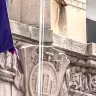 Two NYU flags flying above entrance to Frederick Loewe Theatre on New York University campus. 