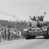 Israeli soldiers driving a tank pass a line of waving civilians on the side of a road while advancing into Syria during the Six Day War, June 1967. 