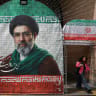 A woman walks next to a banner with a picture of Iran's new Supreme Leader Mojtaba Khamenei in Tehran, Iran, May 8, 2026. 