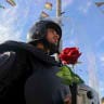 A riot police officer stands near residents during a ceremony marking the 11th anniversary of what participants describe as the liberation of Jericho, also known as Ariha, in Syria's northwestern Idlib province, on May 28, 2026. 