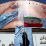 A woman holds an Iranian flag near an anti-US billboard depicting US President Donald Trump and the Strait of Hormuz, in Tehran, Iran, May 25, 2026. 