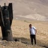 A man checks a fallen rocket half-buried in the ground in the West Bank on June 8, 2026, following Iranian and Iran-backed Houthi attacks.