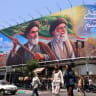 People cross the street past a large billboard showing portraits of Iran's late supreme leader, Ayatollah Ruhollah Khomeini (L) and slain supreme leader Ayatollah Ali Khamenei (R) in central Tehran on June 8, 2026.