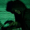 A man holds a laptop computer as cyber code is projected on him in this illustration picture.