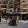 A man in a wheelchair passes by as emergency personnel work at the site of an Israeli strike on the southern suburbs of Beirut, Lebanon, June 7, 2026.