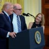 : U.S. President Donald Trump (L) and Julie Strauss Levin (R) look on as conservative radio host Mark Levin (C) speaks during a Hanukkah Reception in the East Room of the White House on December 16, 2025 in Washington, DC. 