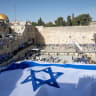 People hold a giant Israeli national flag at the Western Wall in Jerusalem Old City, on the eve of Jerusalem Day, May 14, 2026.