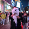 A man holds a dog whilst walking along a street in Shanghai on March 25, 2026.
