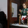 A woman cleans a glass cabinet with a baby Jesus statue dressed in a version of the national soccer team jersey at a church in Mexico City June 12, 2014. Catholic soccer fans pray before the statue, which believers say has granted miracles in the past.