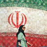 TOPSHOT-IRAN-US-ISRAEL-WAR TOPSHOT - An woman walks past a billboard displaying Iran's national flag at Enghelab Square in Tehran on June 14, 2026. US President Donald Trump said that a deal with Iran to end the Middle East war could be signed on June 14, and that the strategic Strait of Hormuz woul