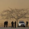Israeli police stand near a dust cloud kicked up by a departing helicopter after the first phase of a ceasefire agreement began between Israel and Hamas on January 19, 2025 near the Gaza border near Re'im, Southern Israel. 