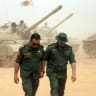 Libyan soldiers walk past tanks as they take part in the "Dara' al-Karama 2" military exercises, conducted by the Libyan National Army (LNA), under the command of Field Marshal Khalifa Haftar, in the Ras al-Alba region in southeastern Libya on May 16, 2026.
