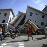 A man carries a mattress past damaged residential buildings following an earthquake in Catia La Mar, La Guaira state, about 30 km northwest of Caracas, on June 25, 2026.