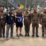 Police officers pose with Carman Simon Peter, an Australian man arrested in the suspected murder of a 17-year-old Thai girl in Pattaya, at Suvarnabhumi International Airport, in Samut Prakan, Thailand June 27, 2026.