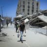 People walk next to the Hamad Towers, north of Khan Yunis in the southern Gaza Strip, which were destroyed by the Israeli military during the war in the Gaza Strip, June 26, 2026. 